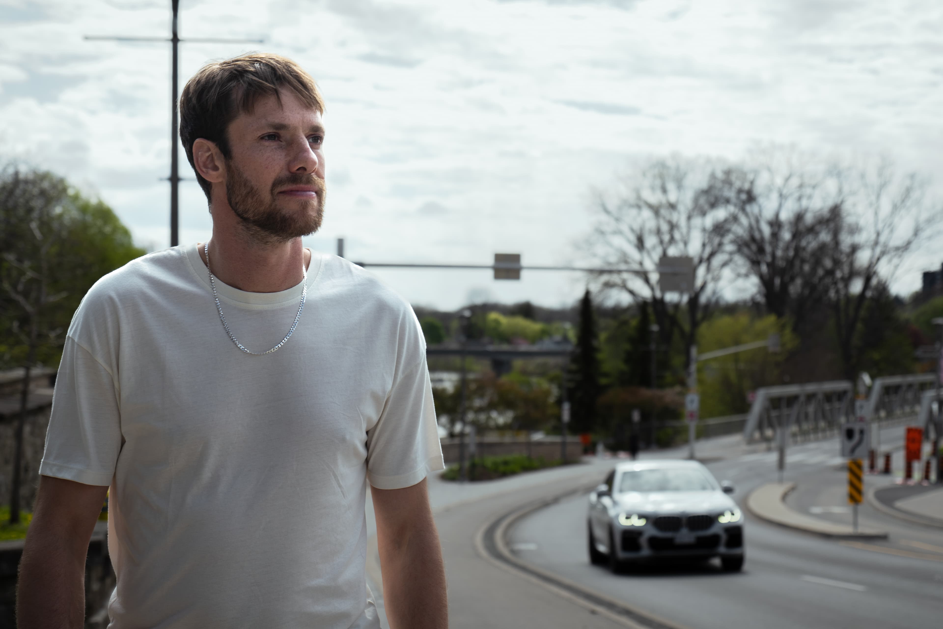 Man beside a road with a car and bridge in the background