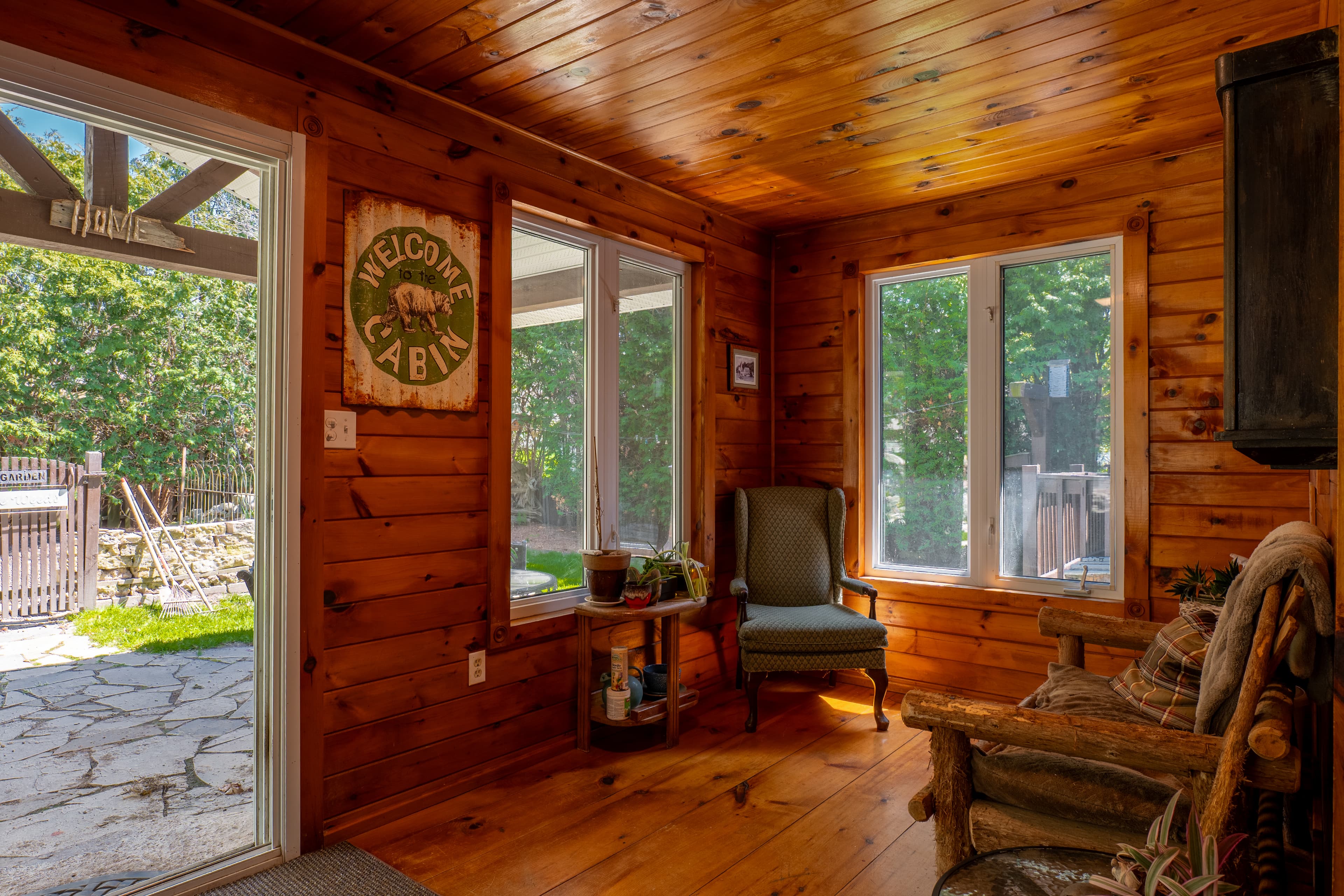 Rustic sunroom with Welcome Cabin sign and large windows